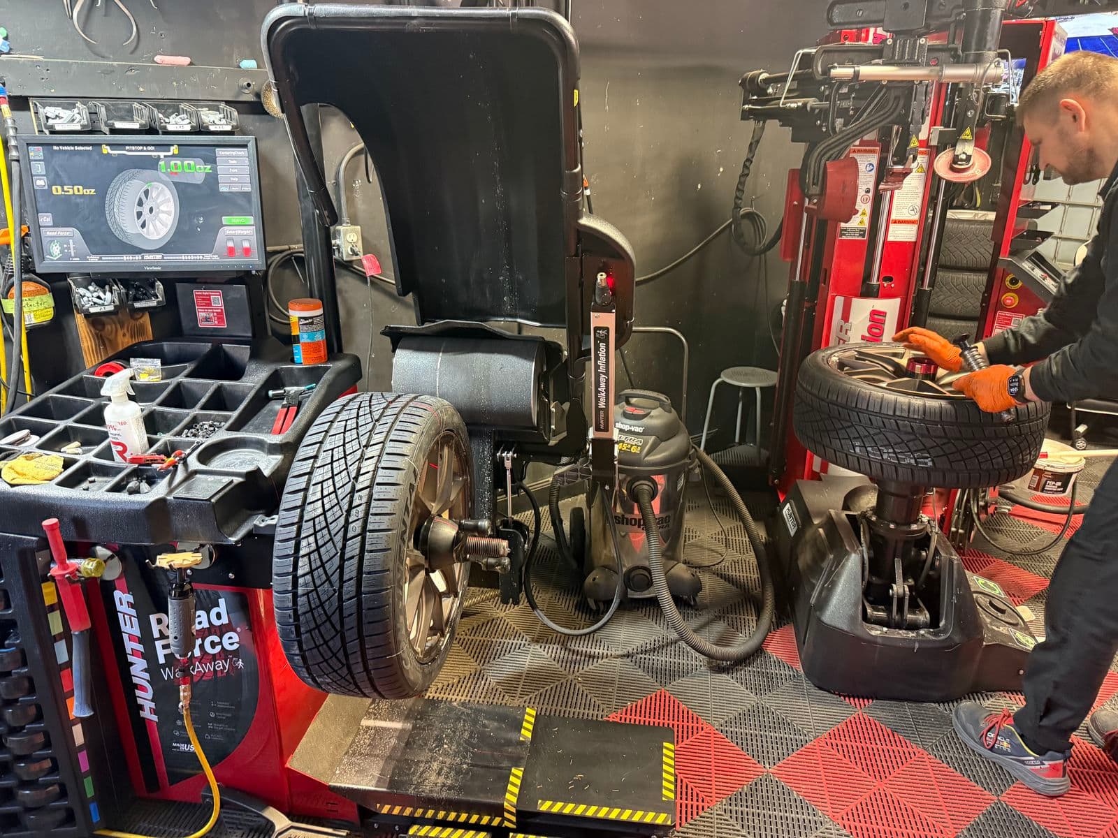 Technician at the Hunter Revolution tire changer beside the Road Force WalkAway balancer