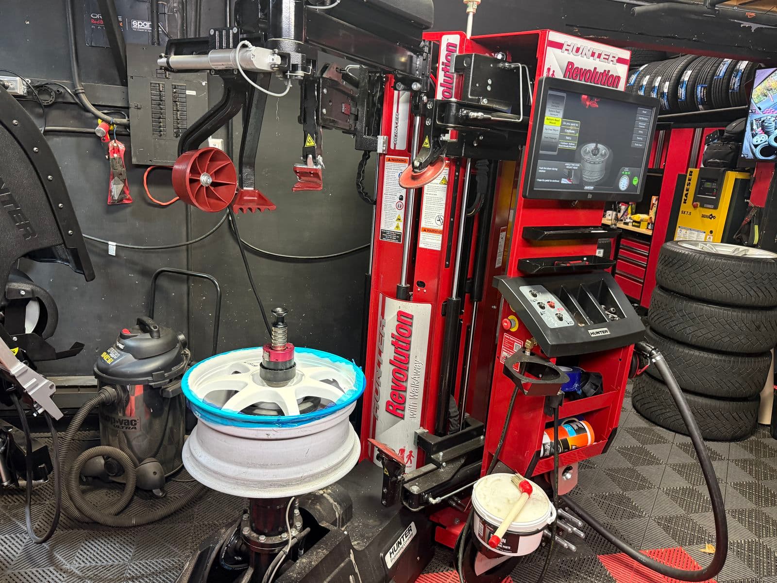 Hunter Revolution tire changer with a white alloy rim clamped