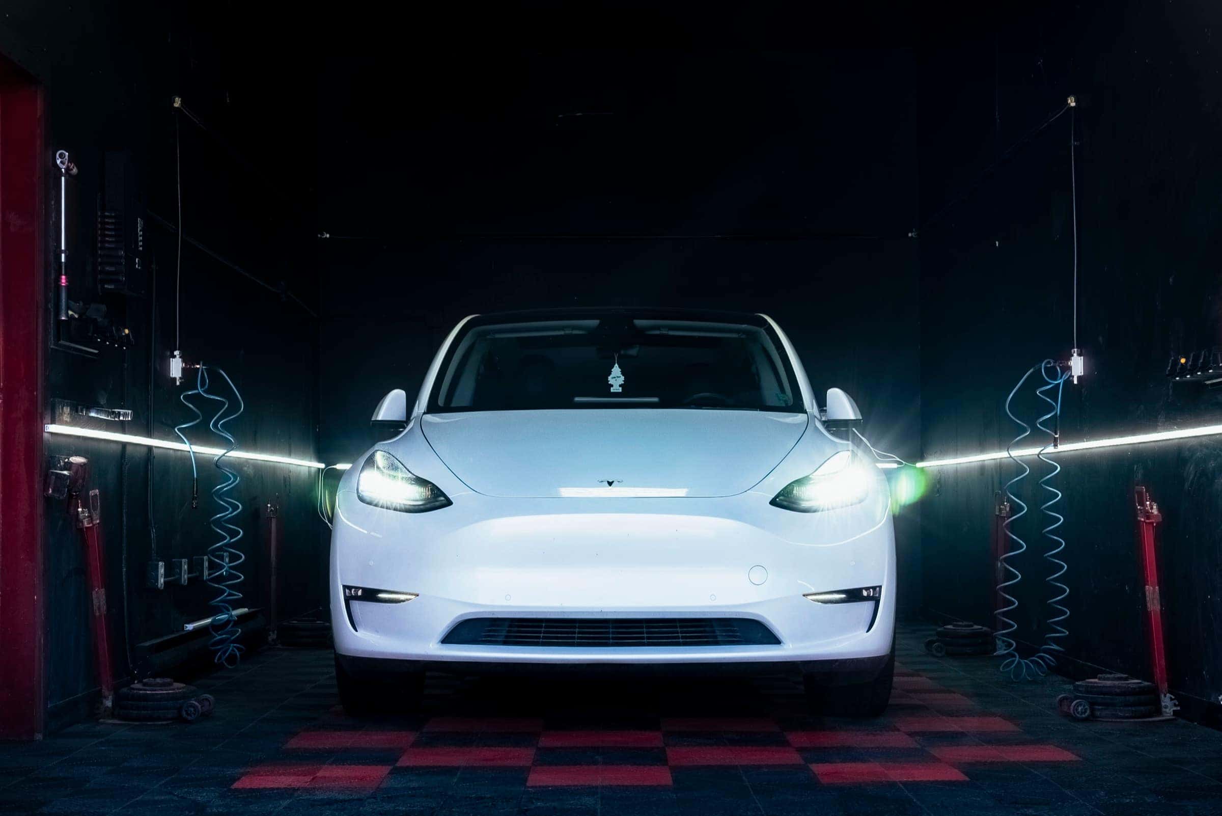 Tesla Model Y front-on in PitStop & Go service bay, moody lighting