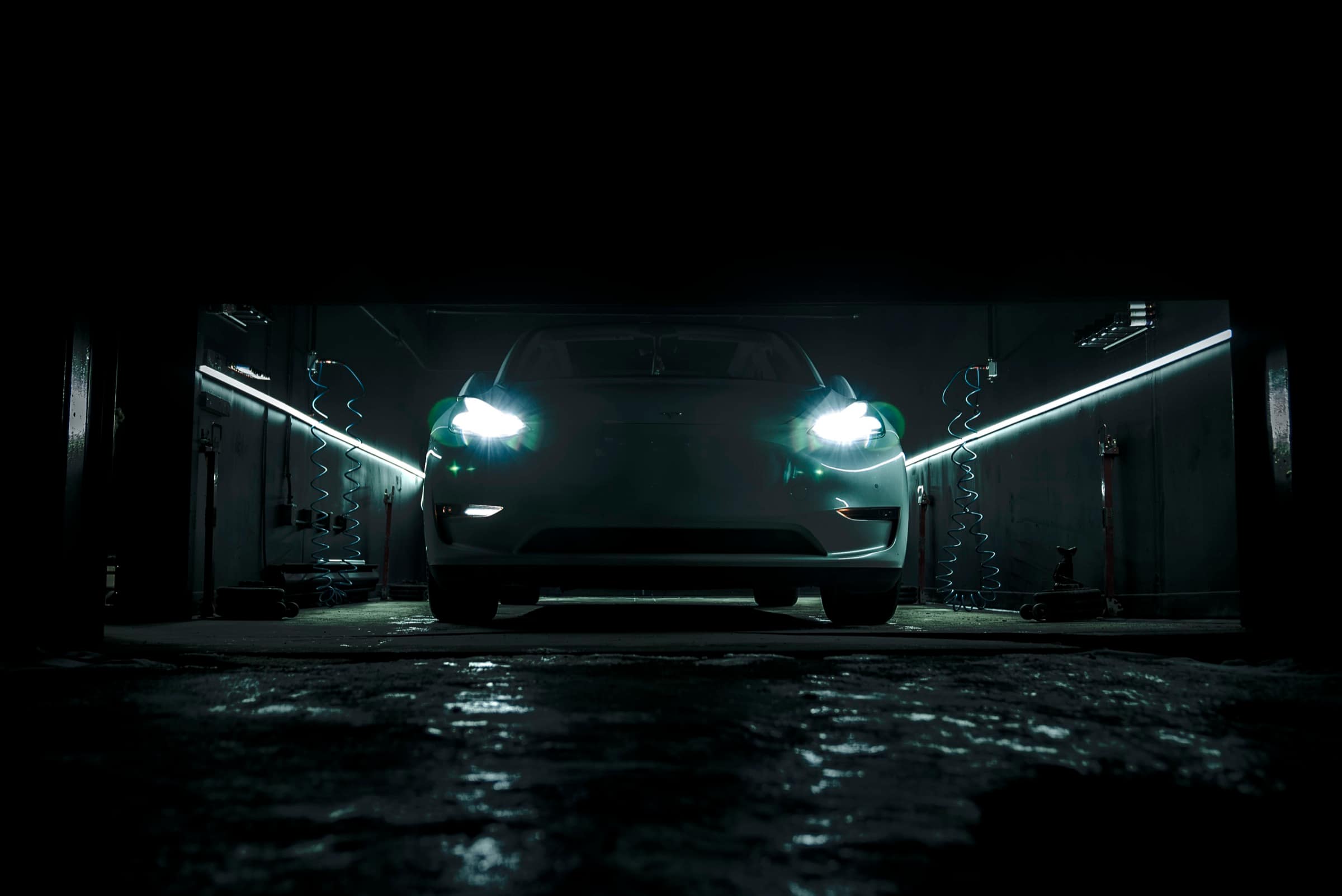 Tesla Model 3 headlights illuminated in the dark service bay
