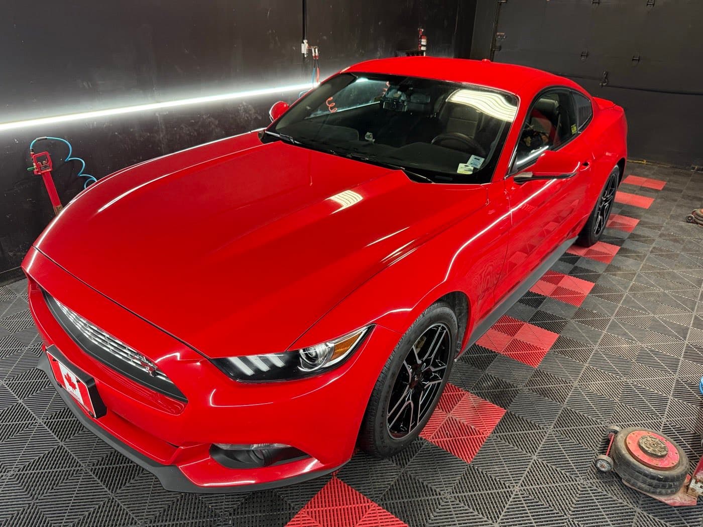 Freshly detailed red Ford Mustang with glossy paint in the PitStop & Go bay