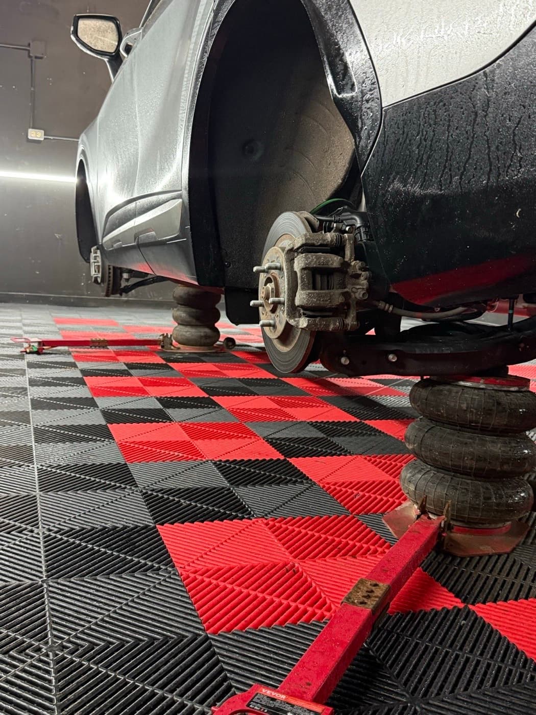 SUV raised on air jacks with all four wheels off for a tire rotation in Fredericton