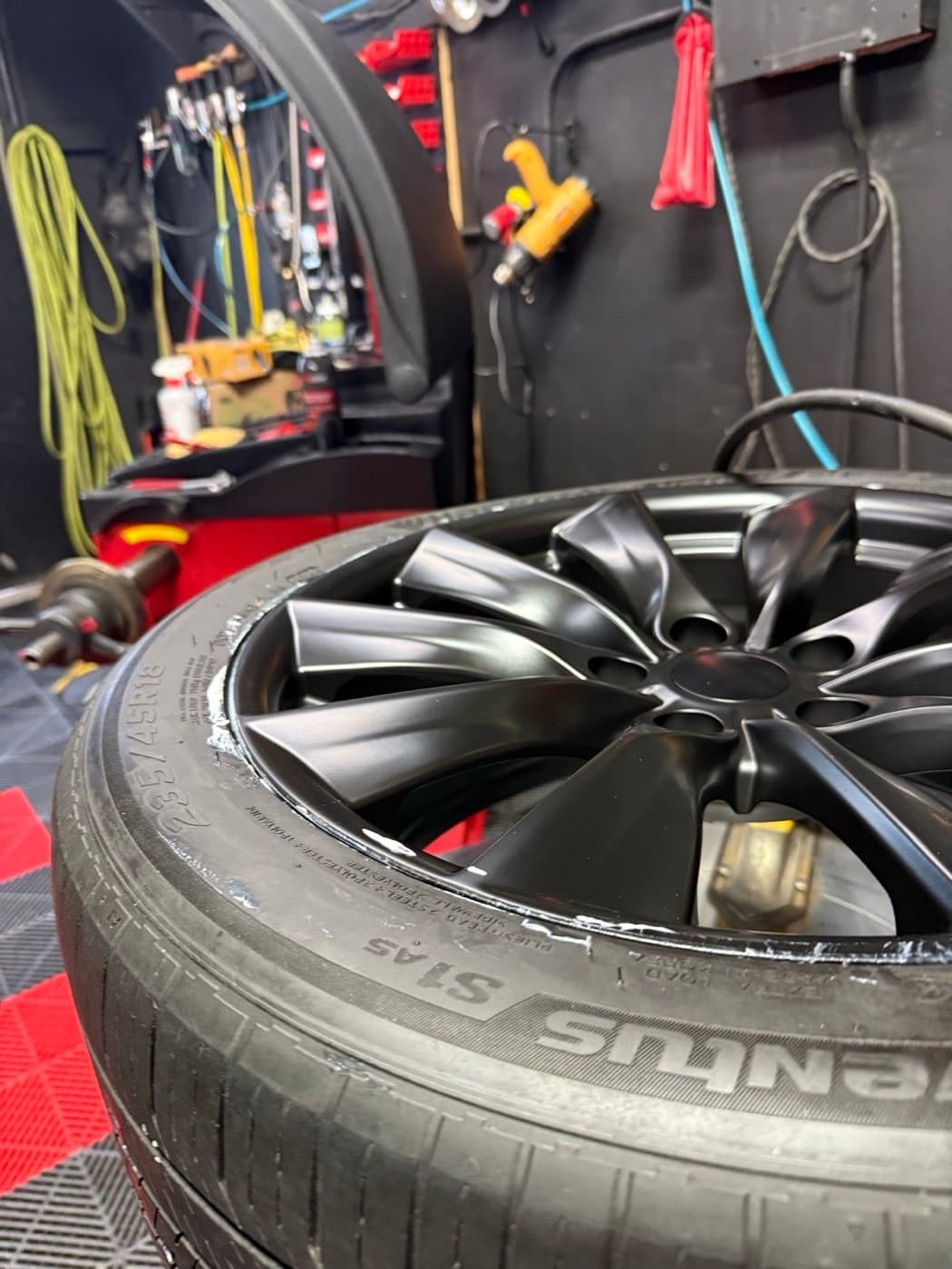Freshly mounted tire on a matte black alloy at PitStop & Go, ready to go back on the car