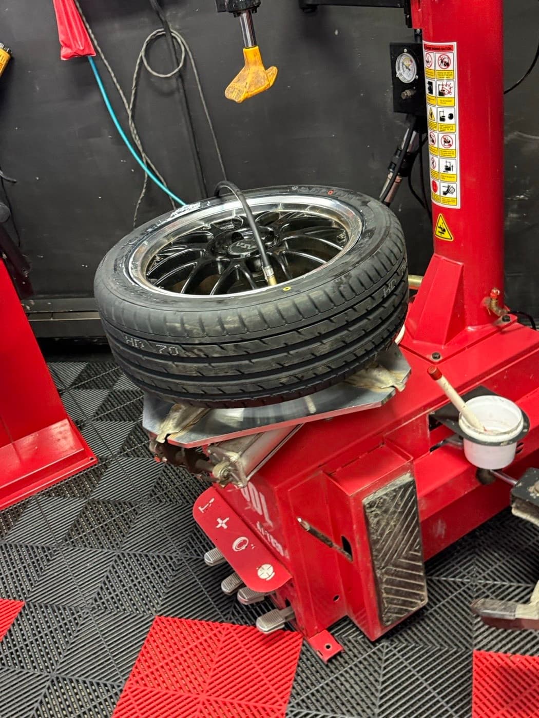 Chrome-lipped alloy wheel with a low-profile tire resting on the tire changer at PitStop & Go in Fredericton