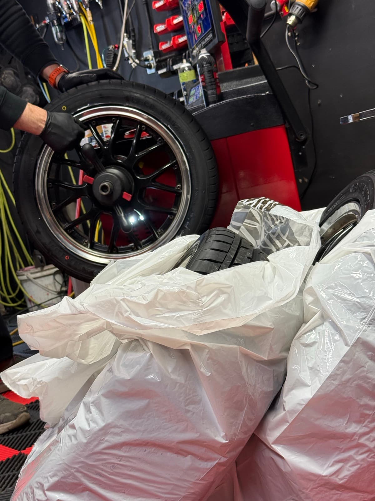 Technician spinning a chrome-lipped rim on the wheel balancer during an on-rim changeover at PitStop & Go