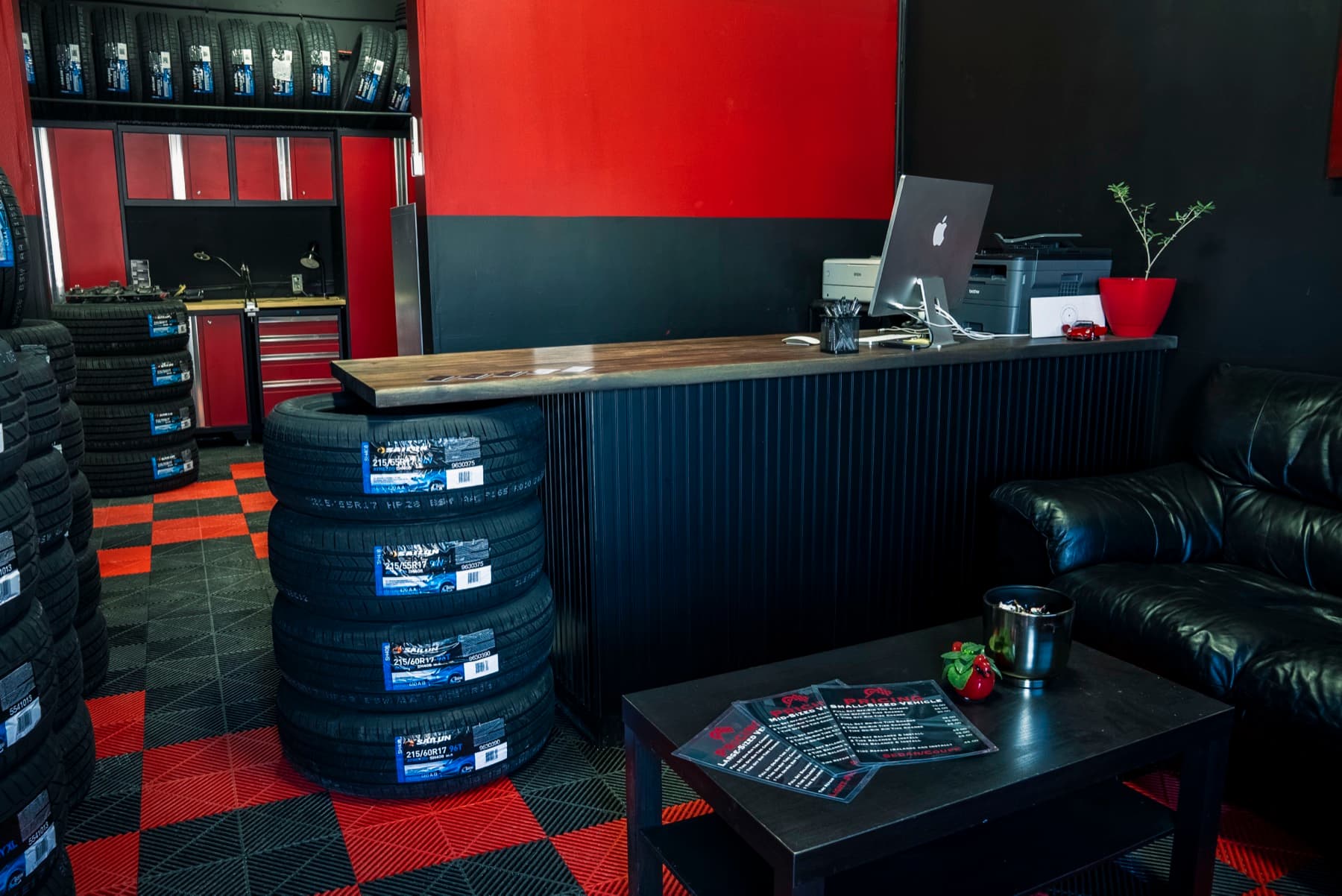PitStop & Go waiting area with iMac counter, leather couch, and Sailun tire stacks